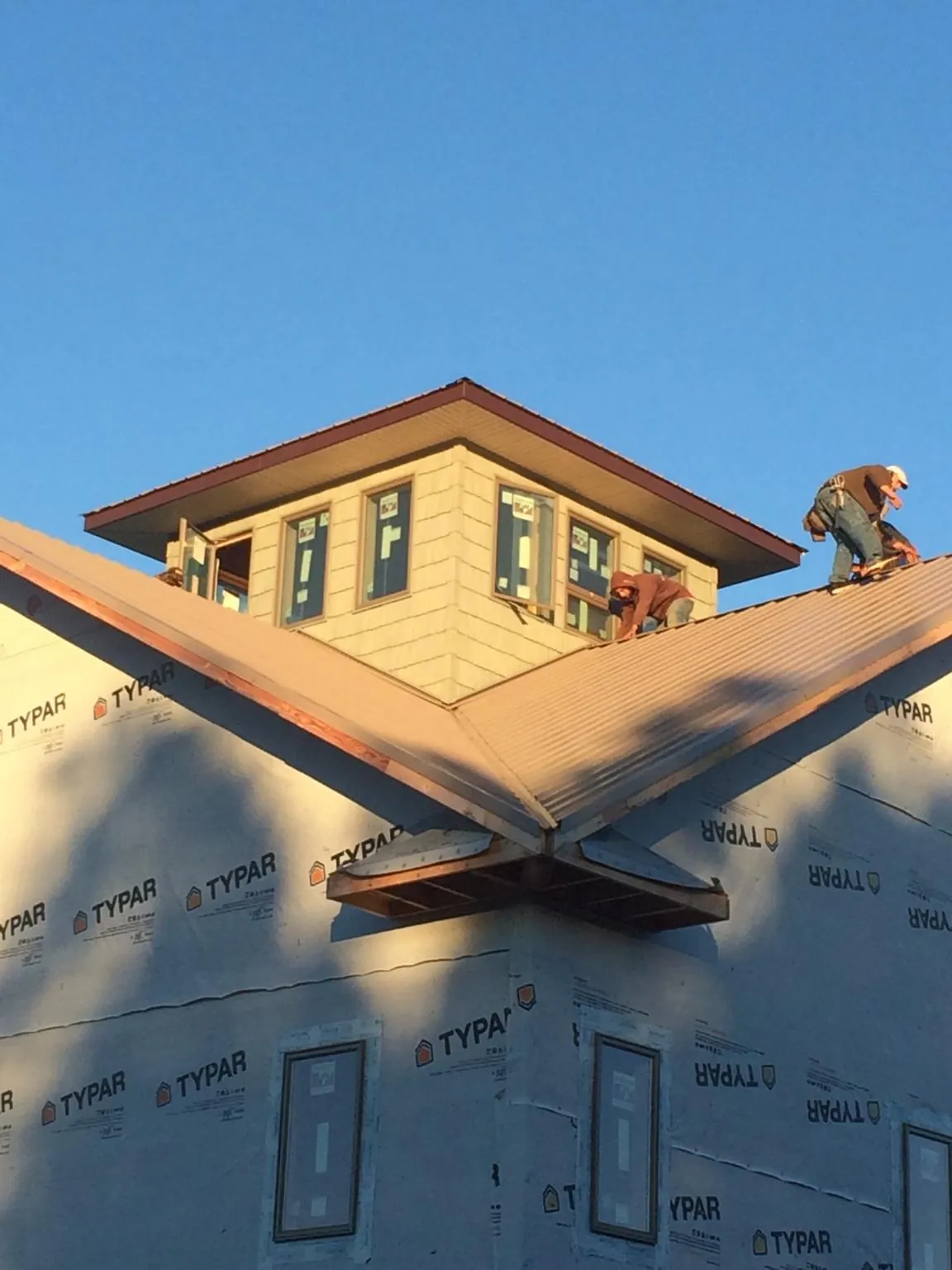 Roofers working around a rooftop cupola on a new metal roof at sunset — Roof Waterproofing in Crestline by Roofing Brothers